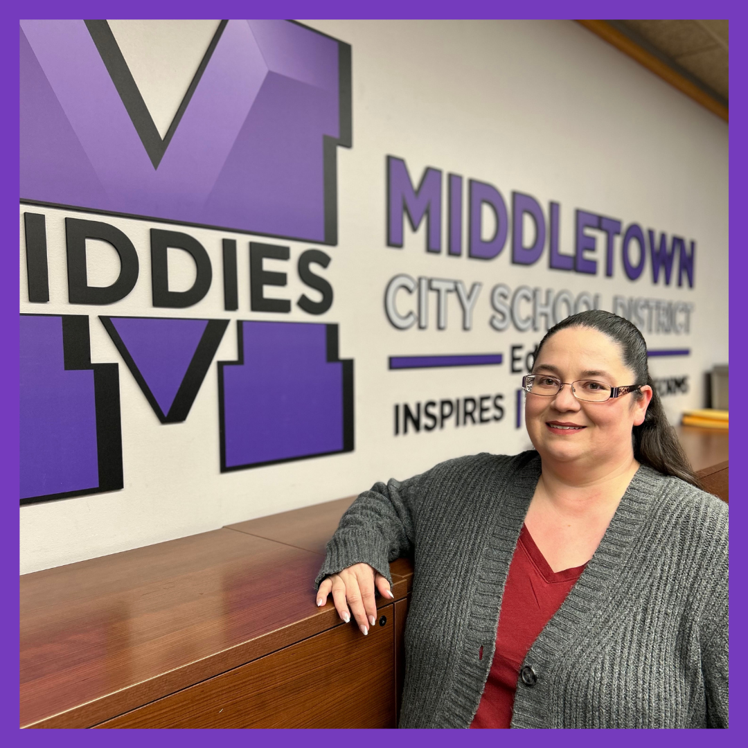 Photo of woman smiling posing with MCSD logo behind her.